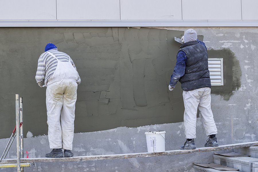 Workers plastering a outdoor wall with trowel